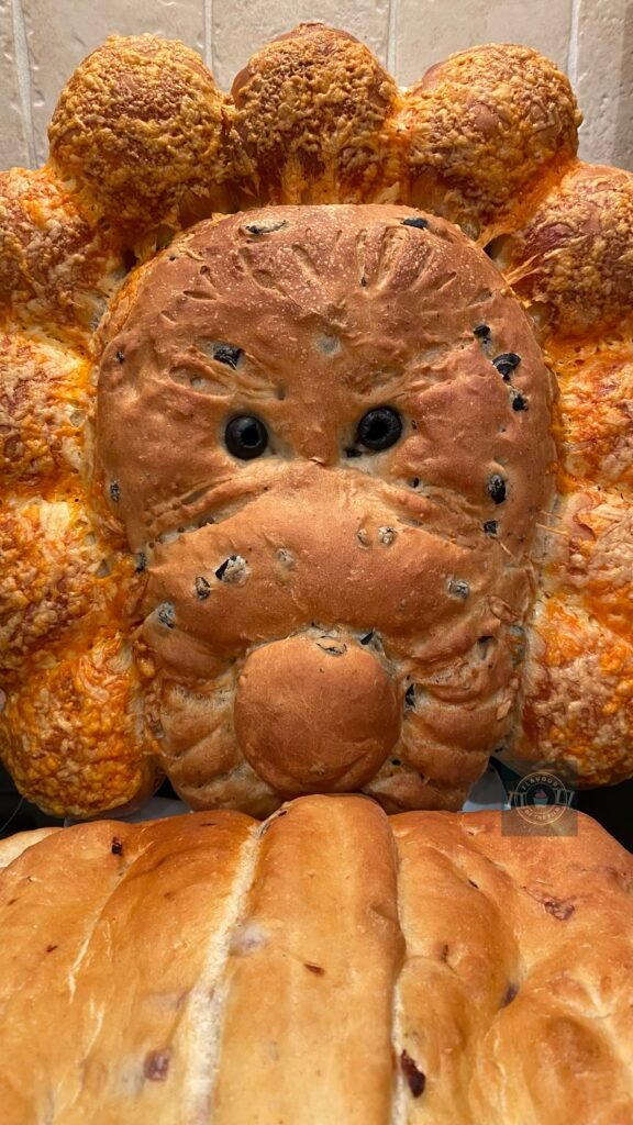 Lion shaped tear and share bread with an olive loaf face, cheese rolls mane and caremalised onion book shaped loaf. This tear and share bread celebrates Narnia: The Lion, The Witch and The Wardrobe.