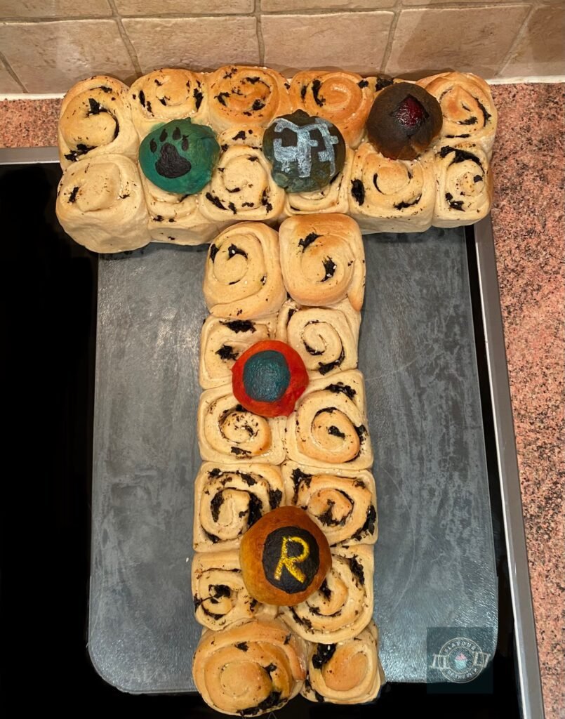 All images are of a seaweed bread with miso in roll shapes, all attached as a tear and share T-Tower, topped with individual glazed rolls painted with logos representing each of the Teen Titans.