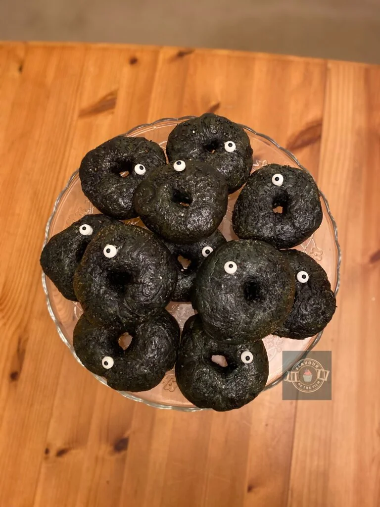 All images are of black sesame seed  bagels topped with black sesame seeds and a single candy googly eye on each one.