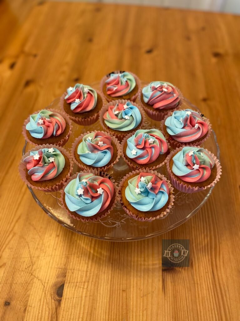 All images are of small cupcakes filled with raspberry jam and topped with buttercream that is a swirl of rose pink, baby blue and mint green colours. The cupcakes are in pink cases on a glass cake stand and each one is finished with three small white candy stars. These cupcakes celebrate The Powerpuff Girls.