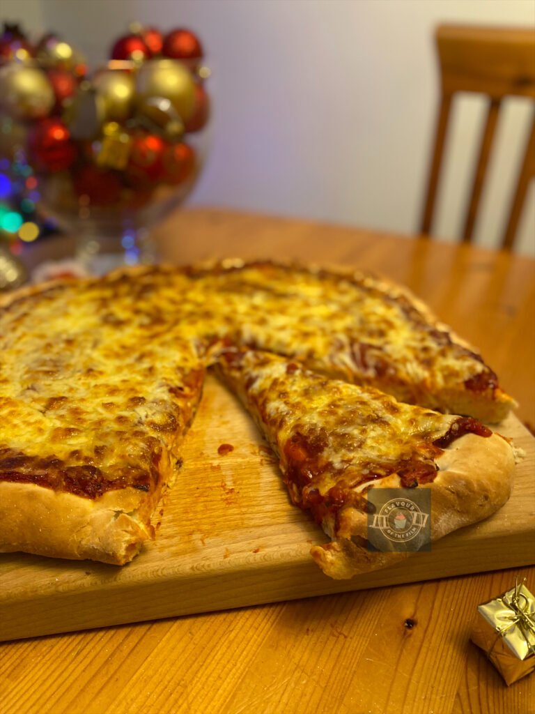 Thick Chicago style cheese pizza with slices cut from it. Christmas baubles are used as props in the background to fit with the Home Alone theme.