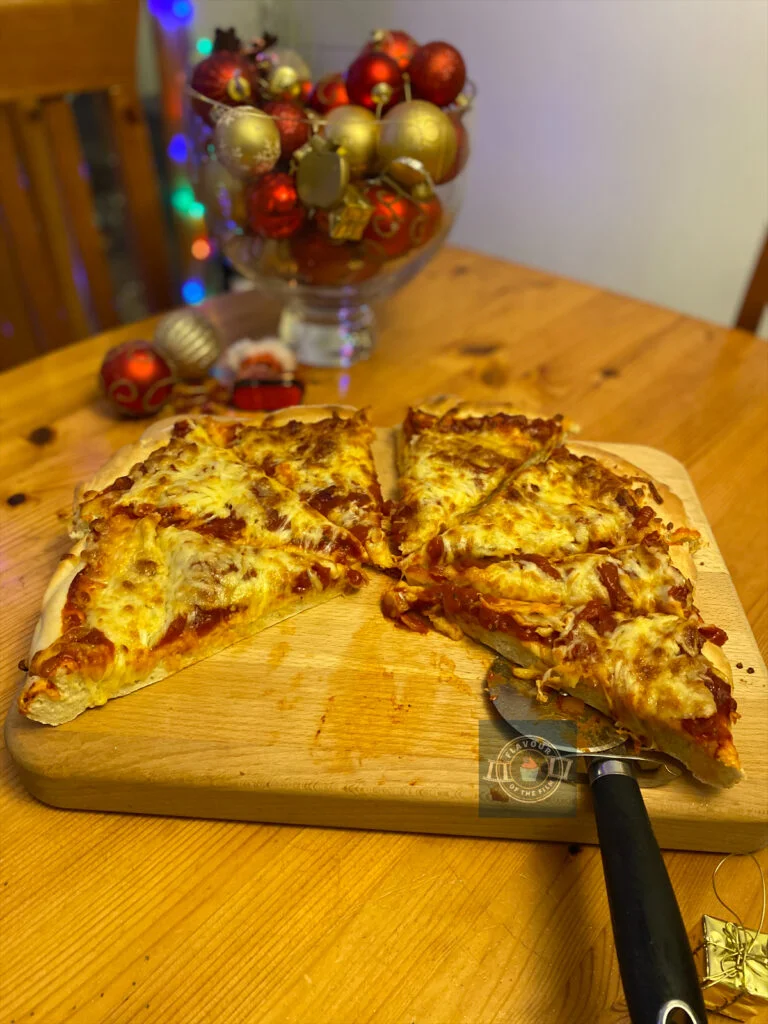 All images are of a large homemade cheese and tomato pizza presented on a wooden board. Props include gold and red Christmas decorations i.e. presents, baubles, snowflakes and multi-coloured Christmas lights.