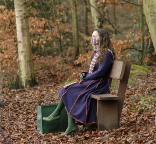 Penelope sitting on a bench surrounded by fallen leaves and trees.