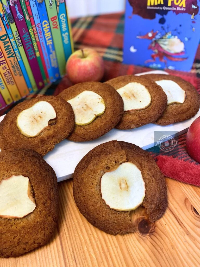 All images are of nutmeg ginger apple snap biscuits with a slice of apple baked in the centre of each one. The biscuits are displayed on a pale wooden board over a tartan blanket. Props include apples and a collection of Roald Dahl books with Fantastic Mr. Fox as the standout.