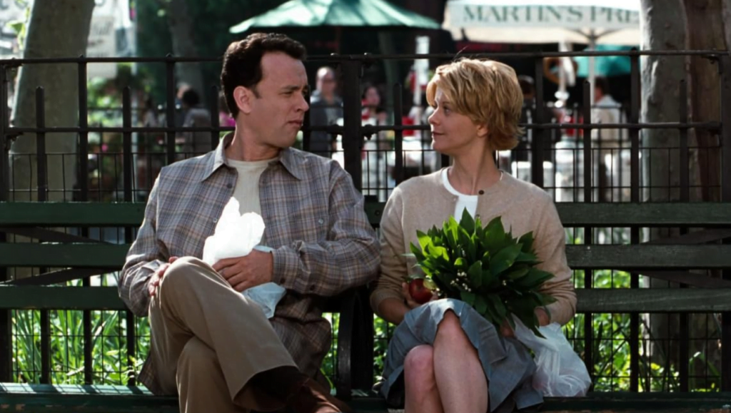 Joe and Kathleen on a park bench eating pretzels and an apple.