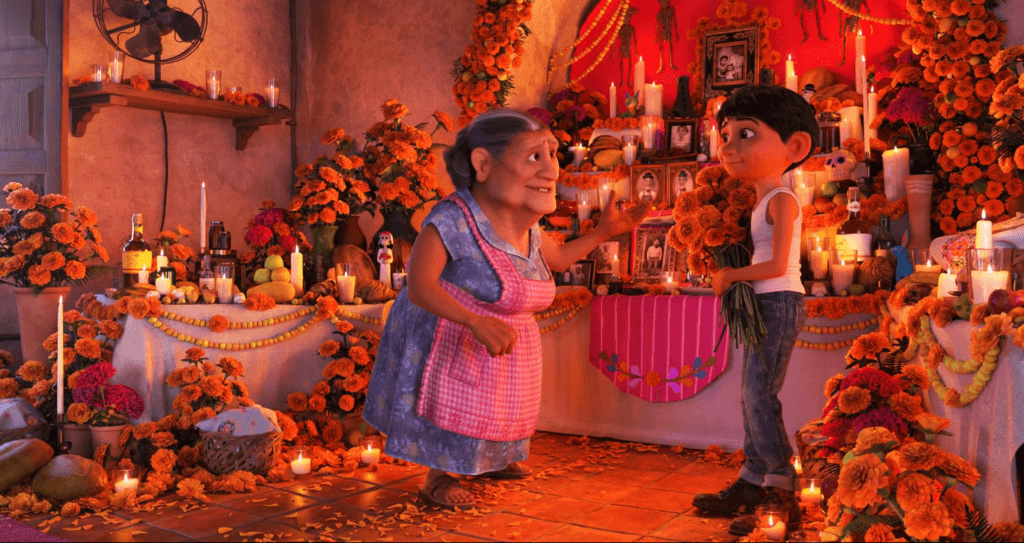 Miguel and his Abuelita standing next to their decorated family ofrenda.