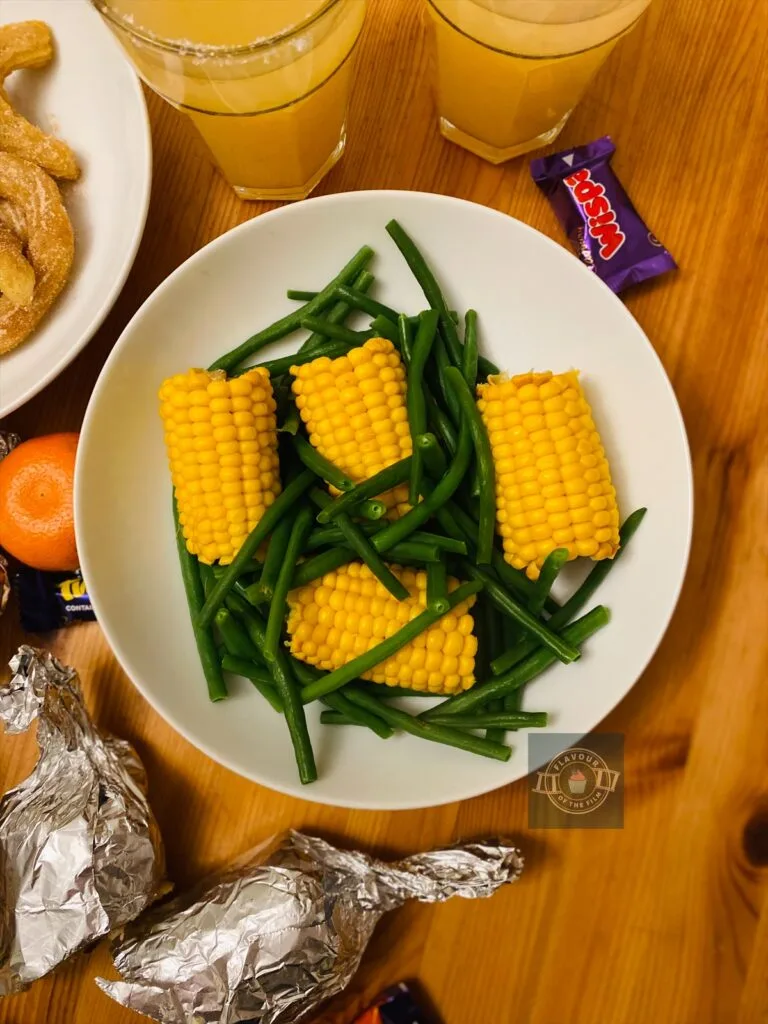 Corn on the cob and green beans in a dish.