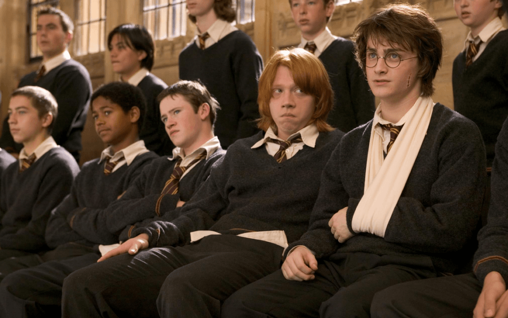 Ron, Harry, Seamus, Dean and more looking less than happy about being told there will be a school dance in Harry Potter and the Goblet of Fire.