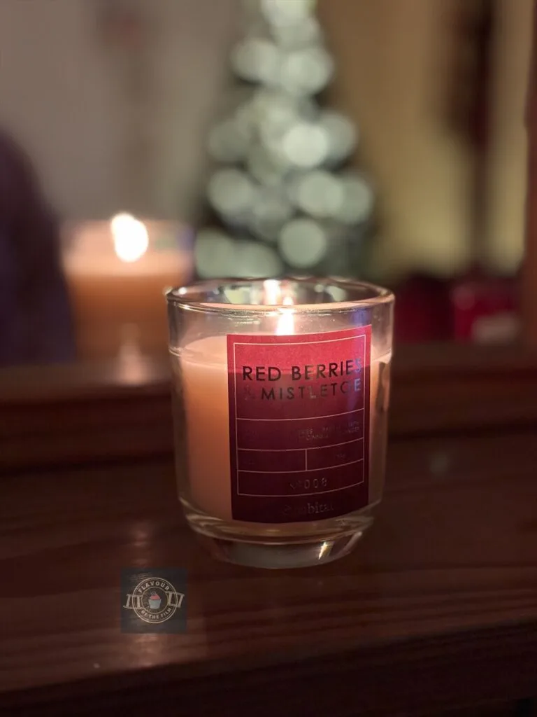 Red berries and mistletoe lit candle.