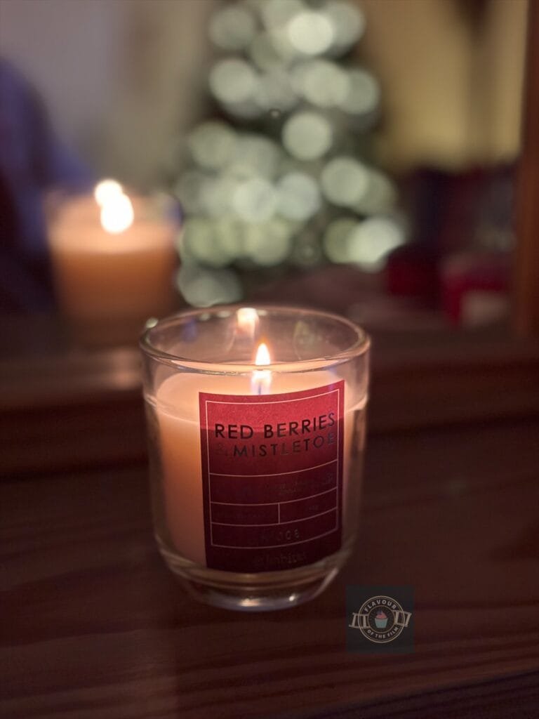 Red berries and mistletoe lit candle.