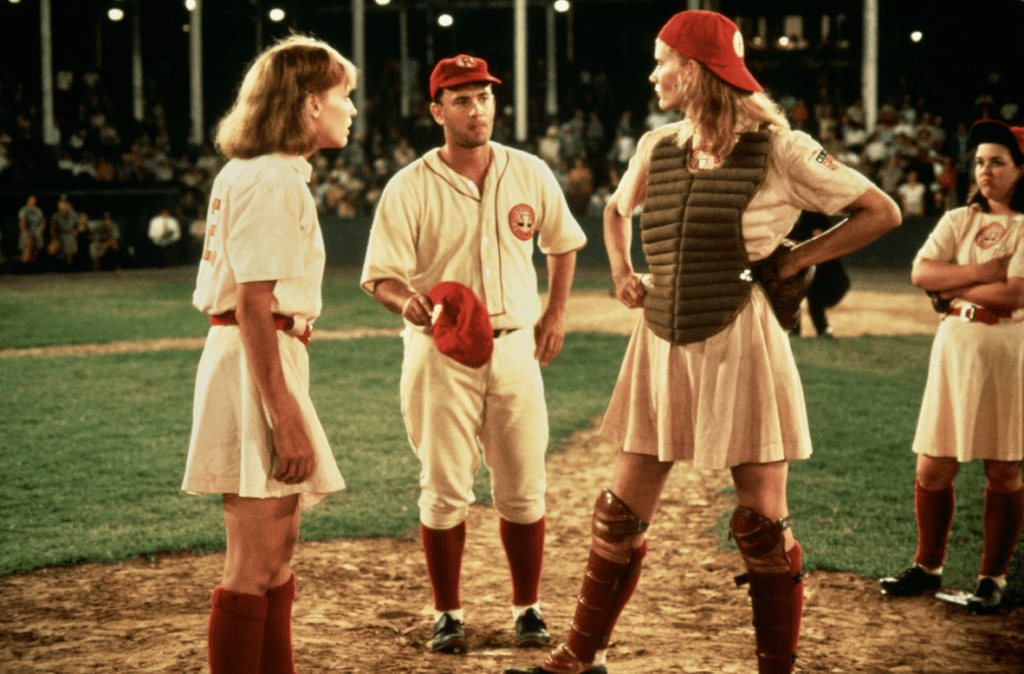 Tom Hanks coaching the female team on the baseball pitch.