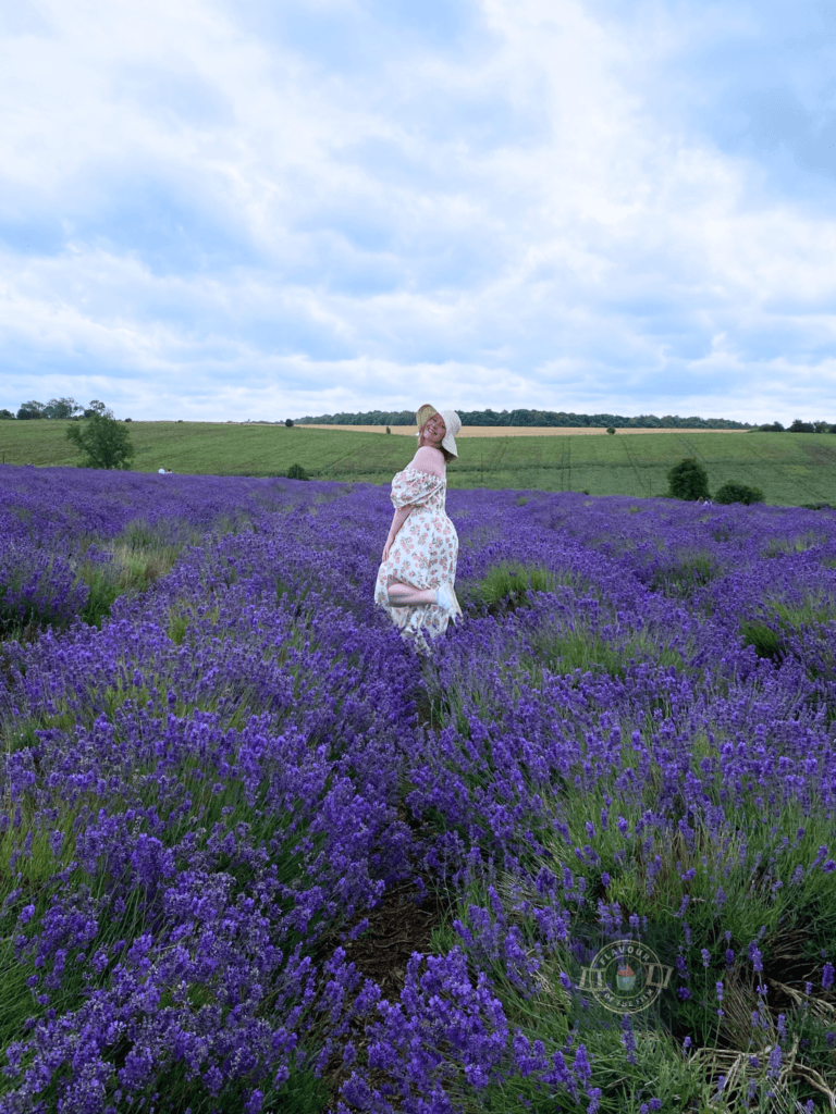 Flavour of the Film creator in a peach print dress and straw hat posing in a lavendar field.