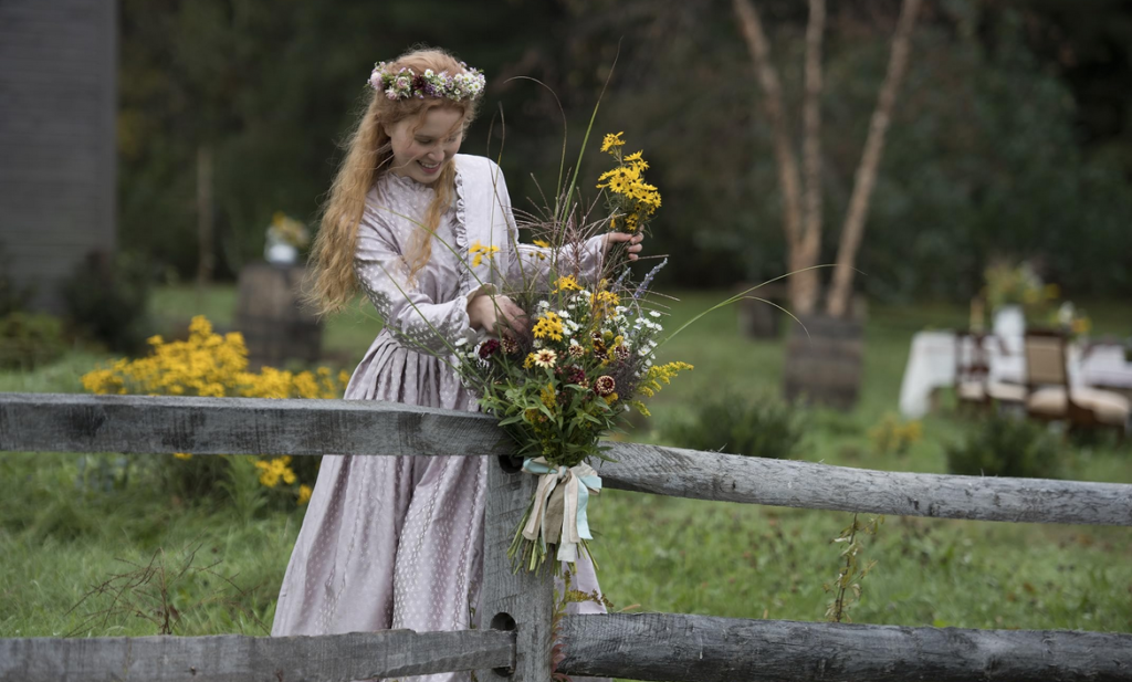 Beth arranging flowers on a fence with flowers in her hair.