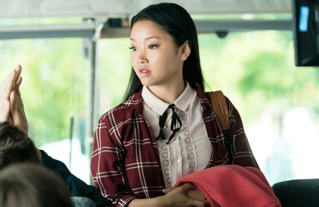 Lara Jean in a red plaid jacket and white frilled blouse with black ribbon bow.