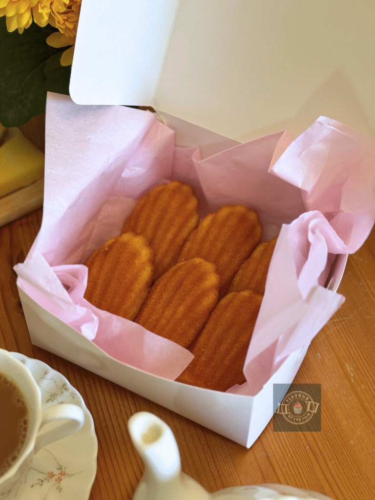 All butter Madeleines served on baby pink tissue paper in a white cardboard box.