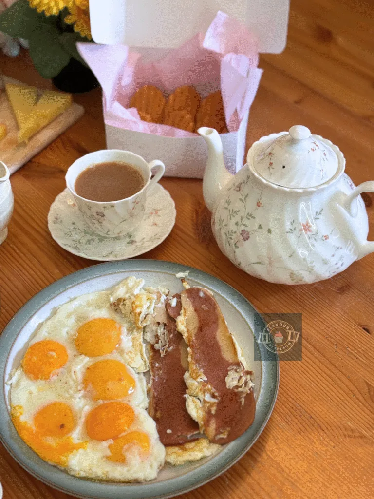 A white floral teapot with matching tea cups on saucers, filled with brewed tea.
