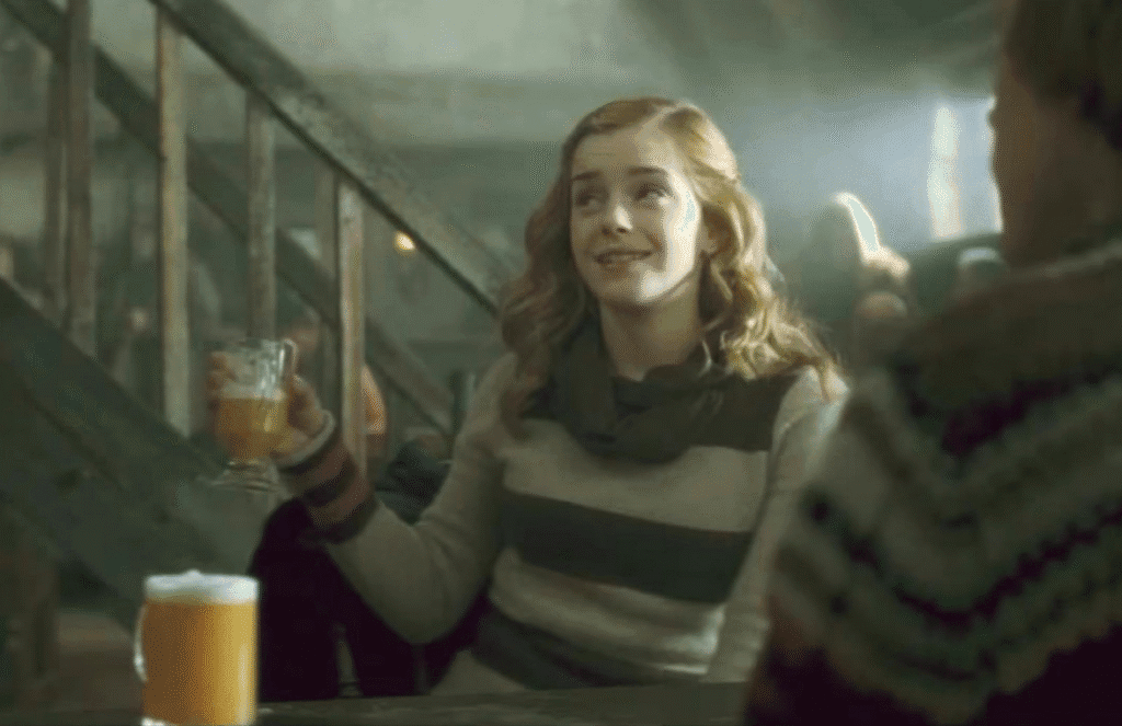 Hermione holding a tankard of butterbeer.