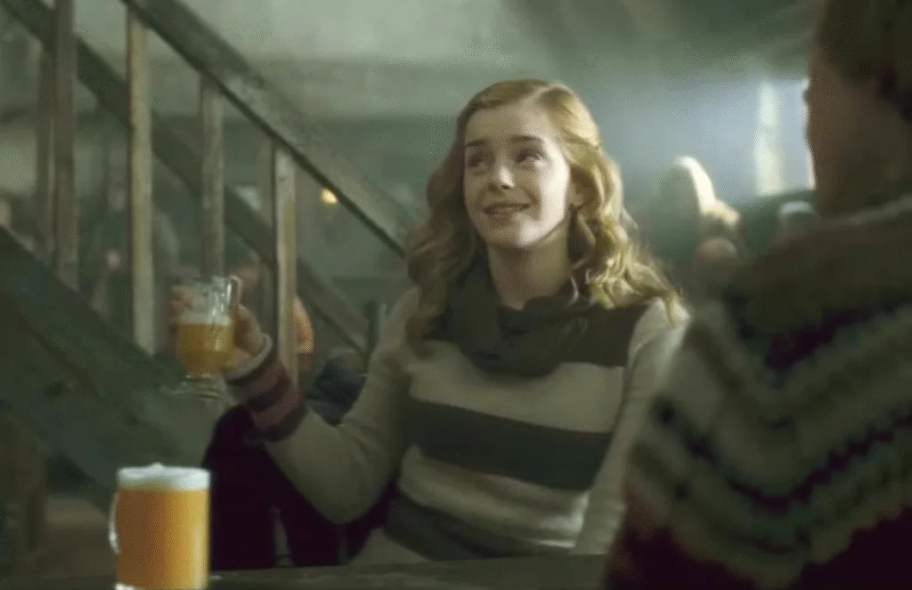 Hermione holding a tankard of butterbeer.