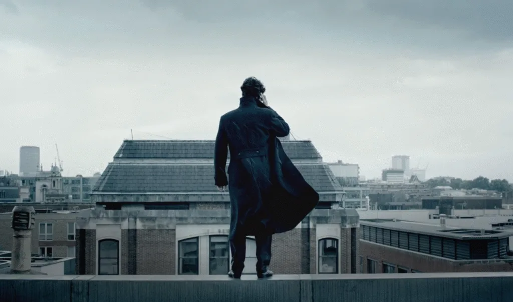 Sherlock standing on the ledge of a building.